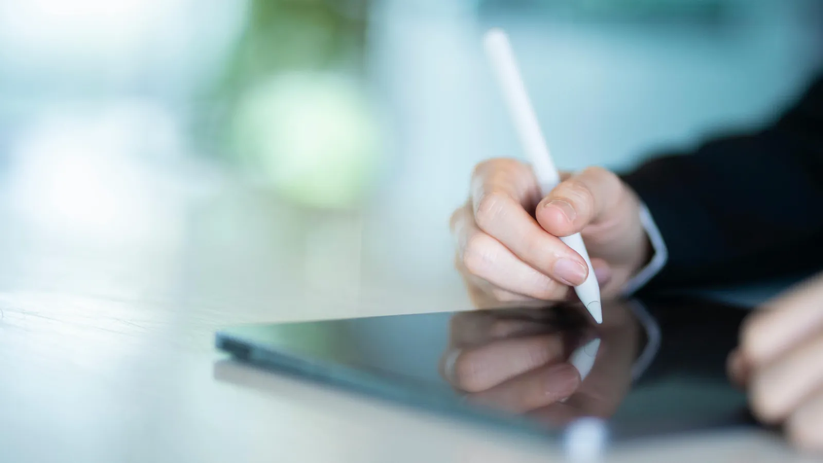 Main qui écrit avec un stylet sur une tablette